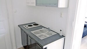 Une cuisine compacte dotée d’une cuisinière intégrée, de deux éviers et d’une poubelle.