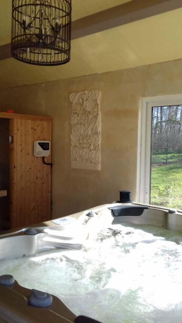 Una habitación con una bañera grande, una puerta de madera y una ventana que da a vistas de árboles.