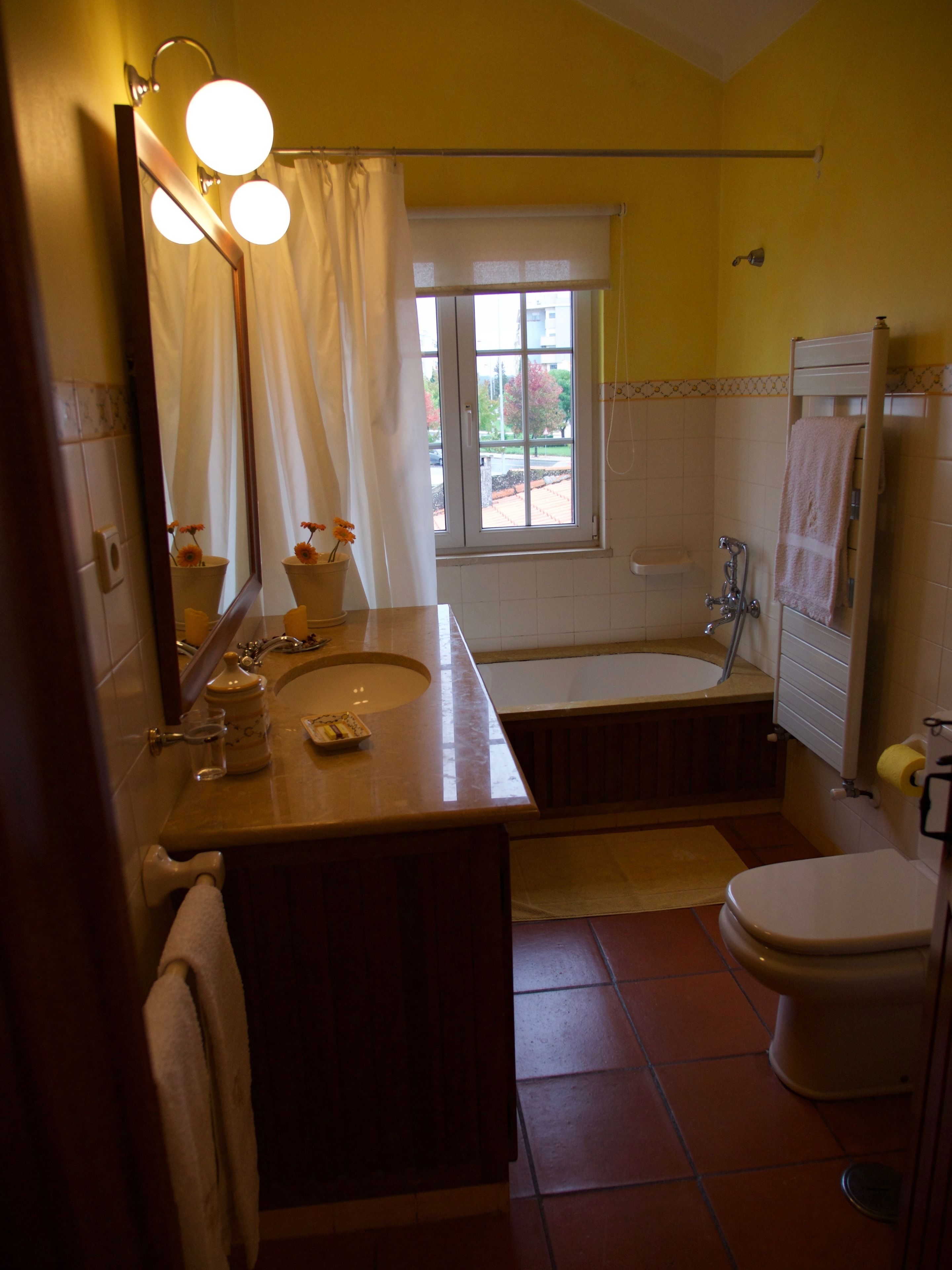 A bathroom with a bathtub, toilet, sink, and a window with a view of the outside.