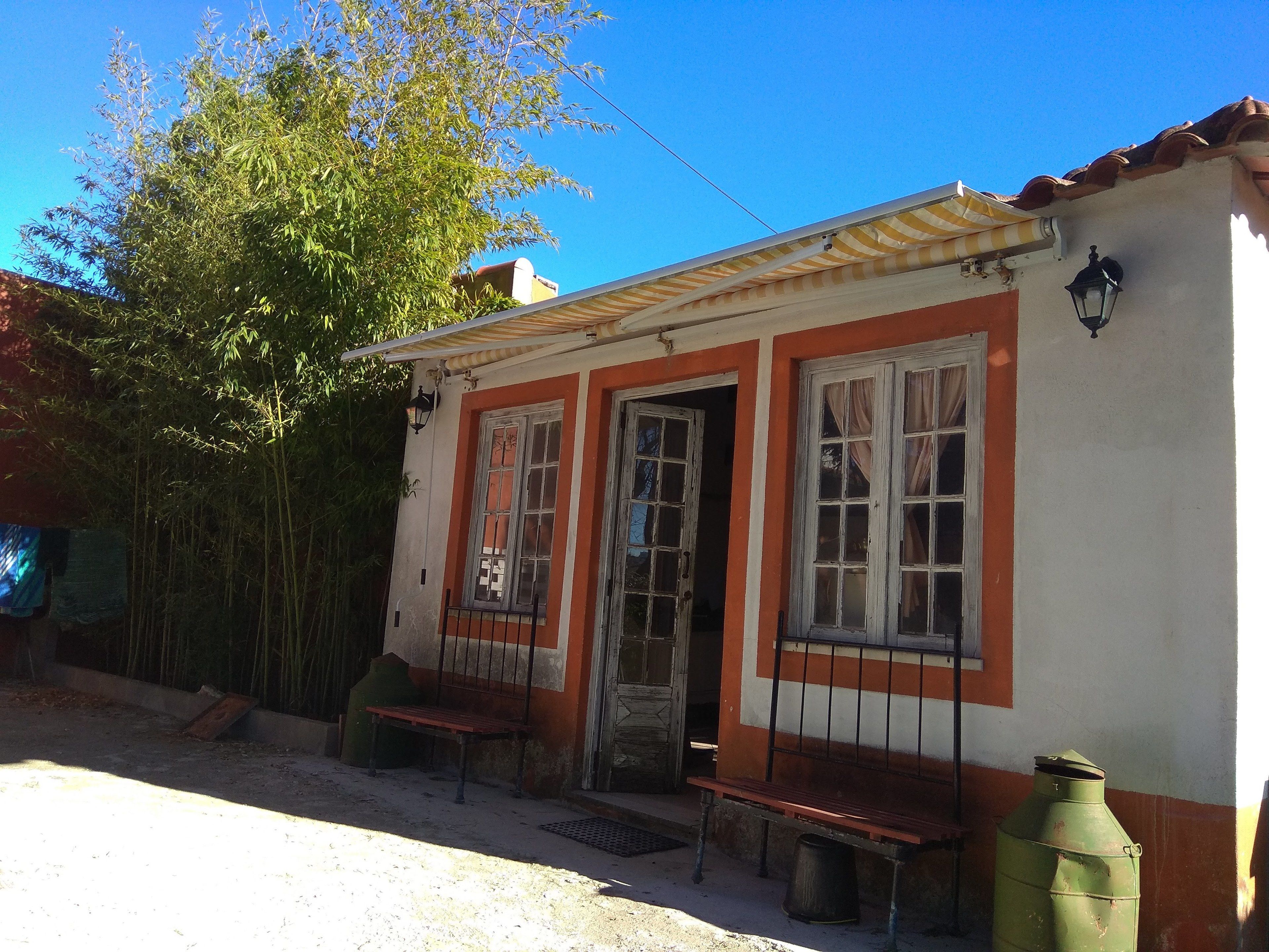 A small building with a tiled roof, a door, and two windows.