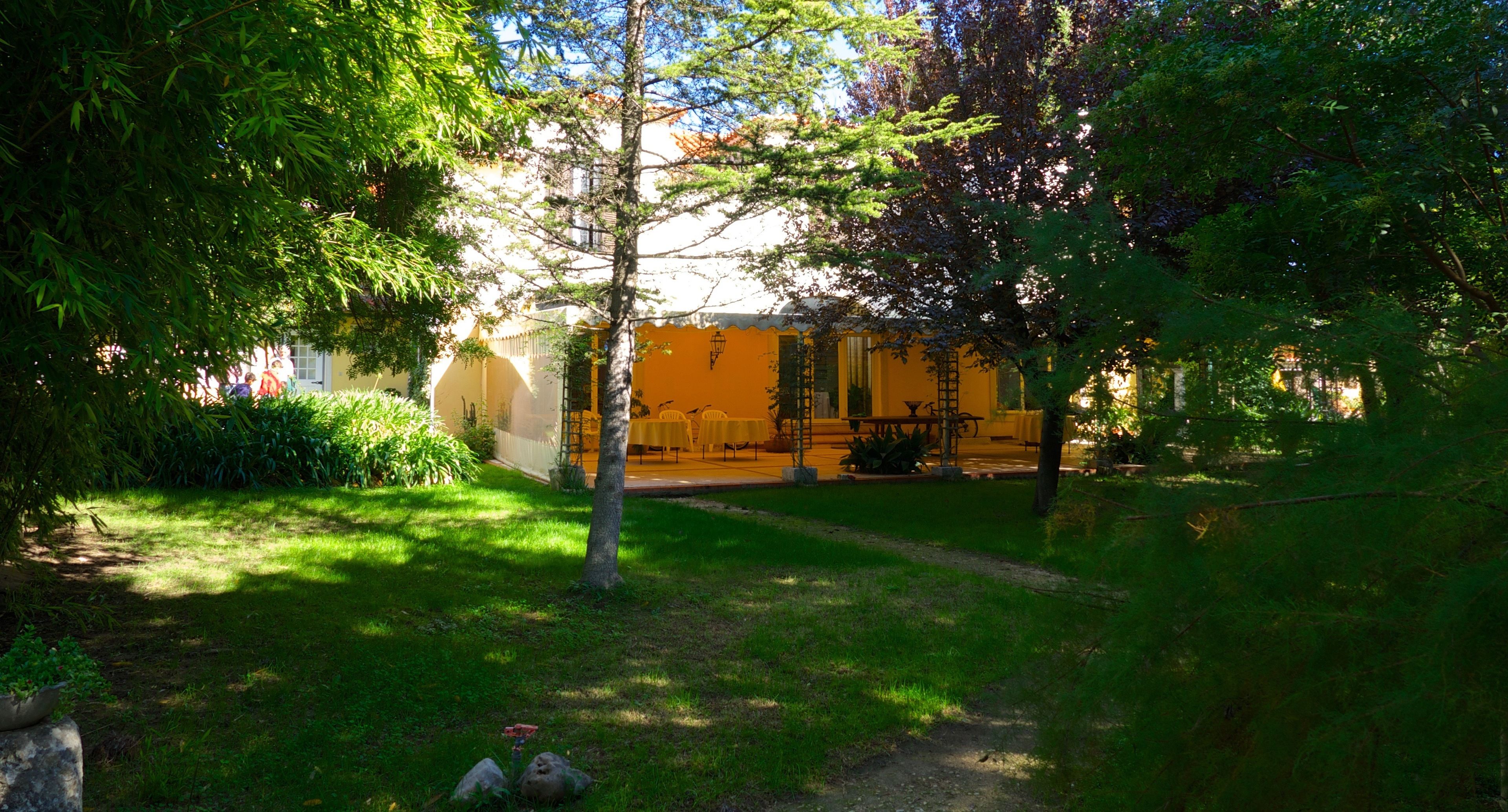 Une cour avec un bâtiment jaune, des sièges en plein air et de la verdure.