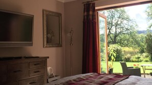 Un dormitorio con cama, cómoda, televisor y ventana con cortinas.