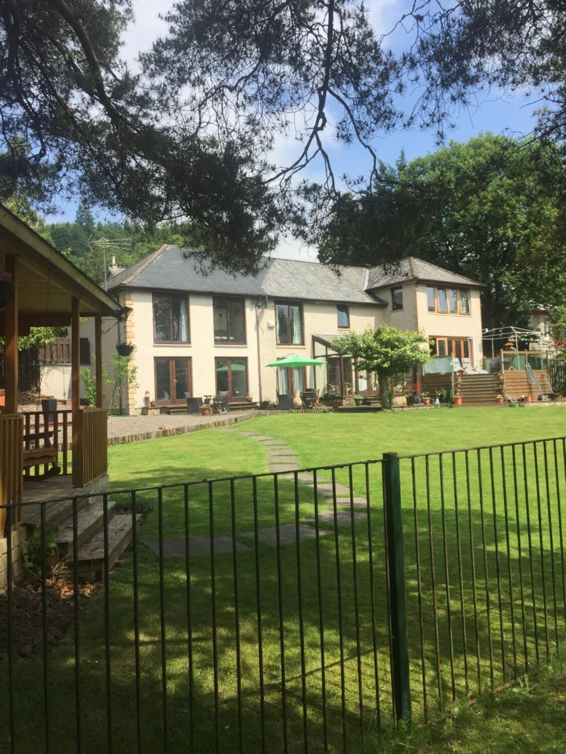 A two-story house with a well-maintained lawn and a wooden deck.