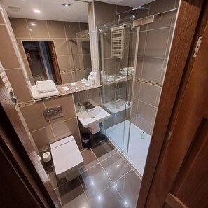 Un baño moderno con cabina de ducha de vidrio, un lavabo e inodoro.