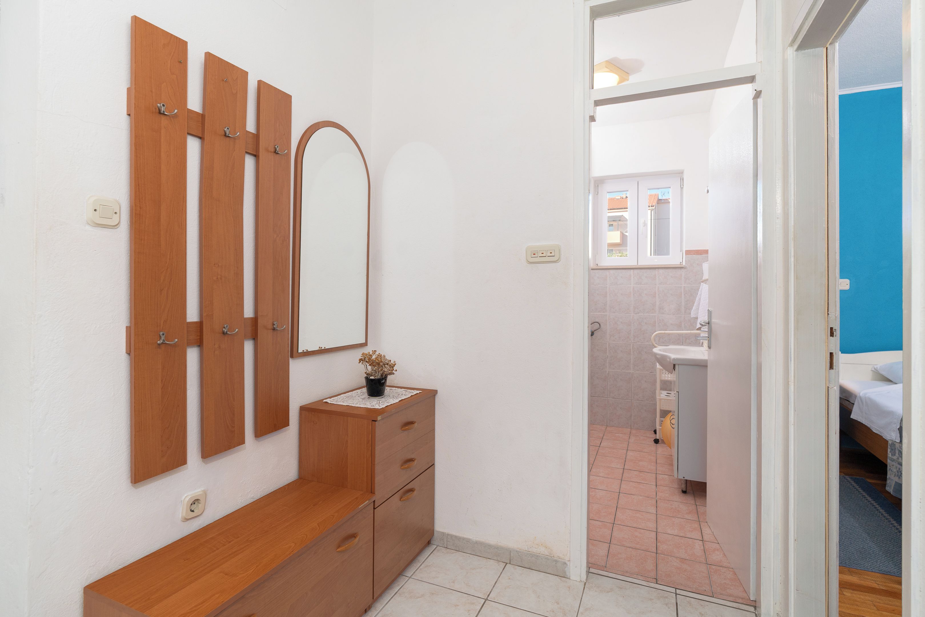 Een badkamer met een wastafel, spiegel en houten opbergmeubel.