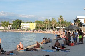 A beach with people sunbathing and swimming. - Apartments Ivanov (Novalja)