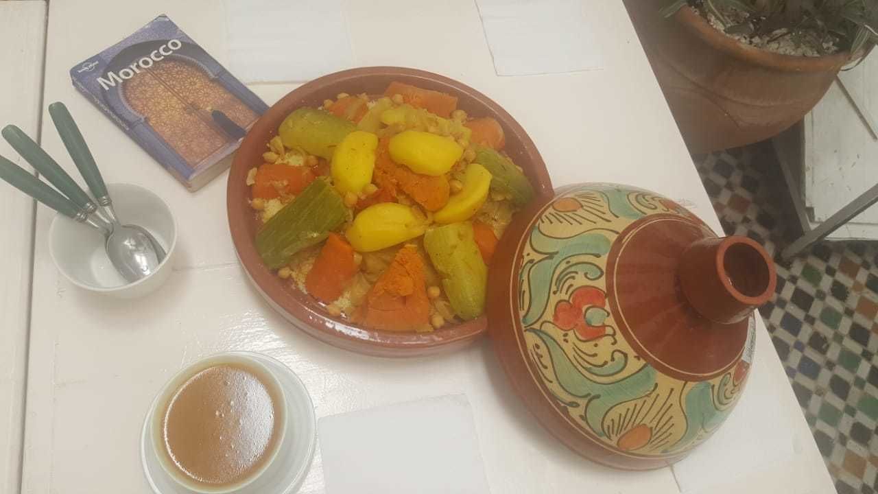 Un tajín marroquí con verduras, una caja de especias, un hervidor de té y un bol pequeño.