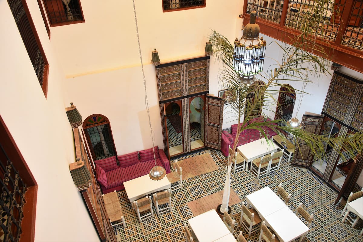A high-ceilinged room with a central seating area, a chandelier, and a patterned floor.