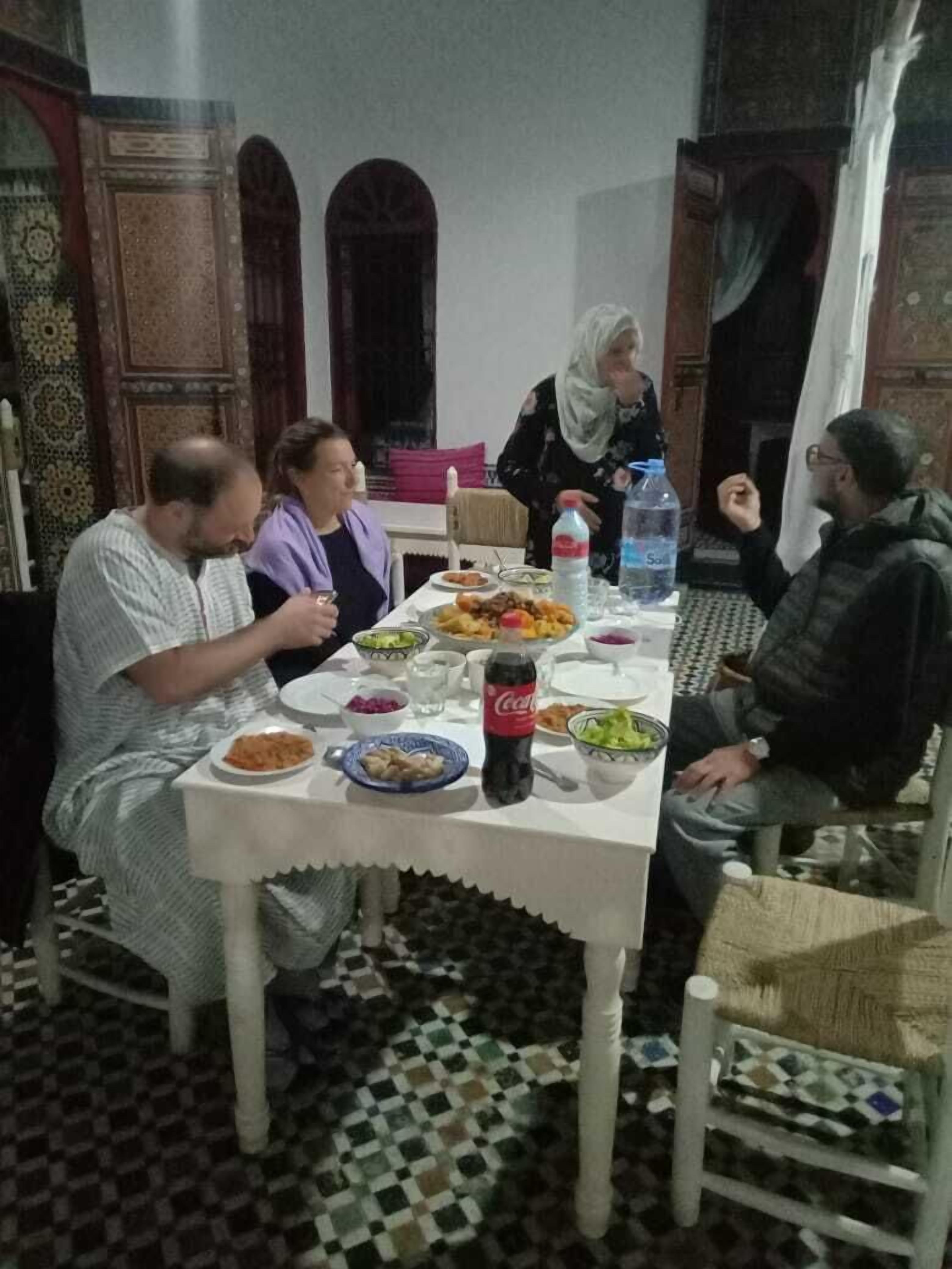 A dining area with a checkered floor, a table set with plates of food, a bottle of Coca-Cola, and a water bottle.