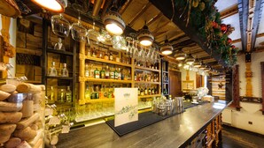 A bar area with wooden shelves stocked with bottles, glasses, and a corkscrew display.