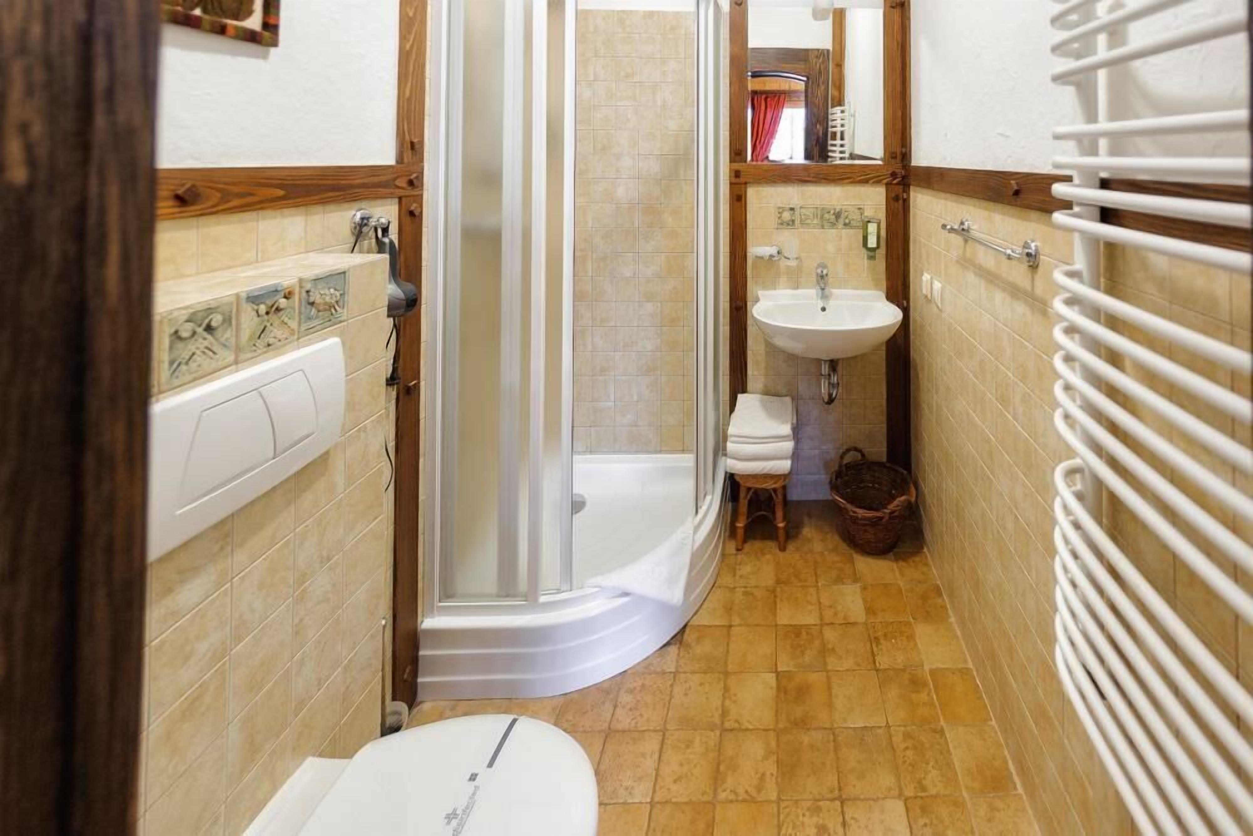 A bathroom with a shower, toilet, sink, and a towel rack.