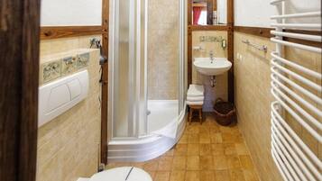 A bathroom with a shower, toilet, sink, and a towel rack.