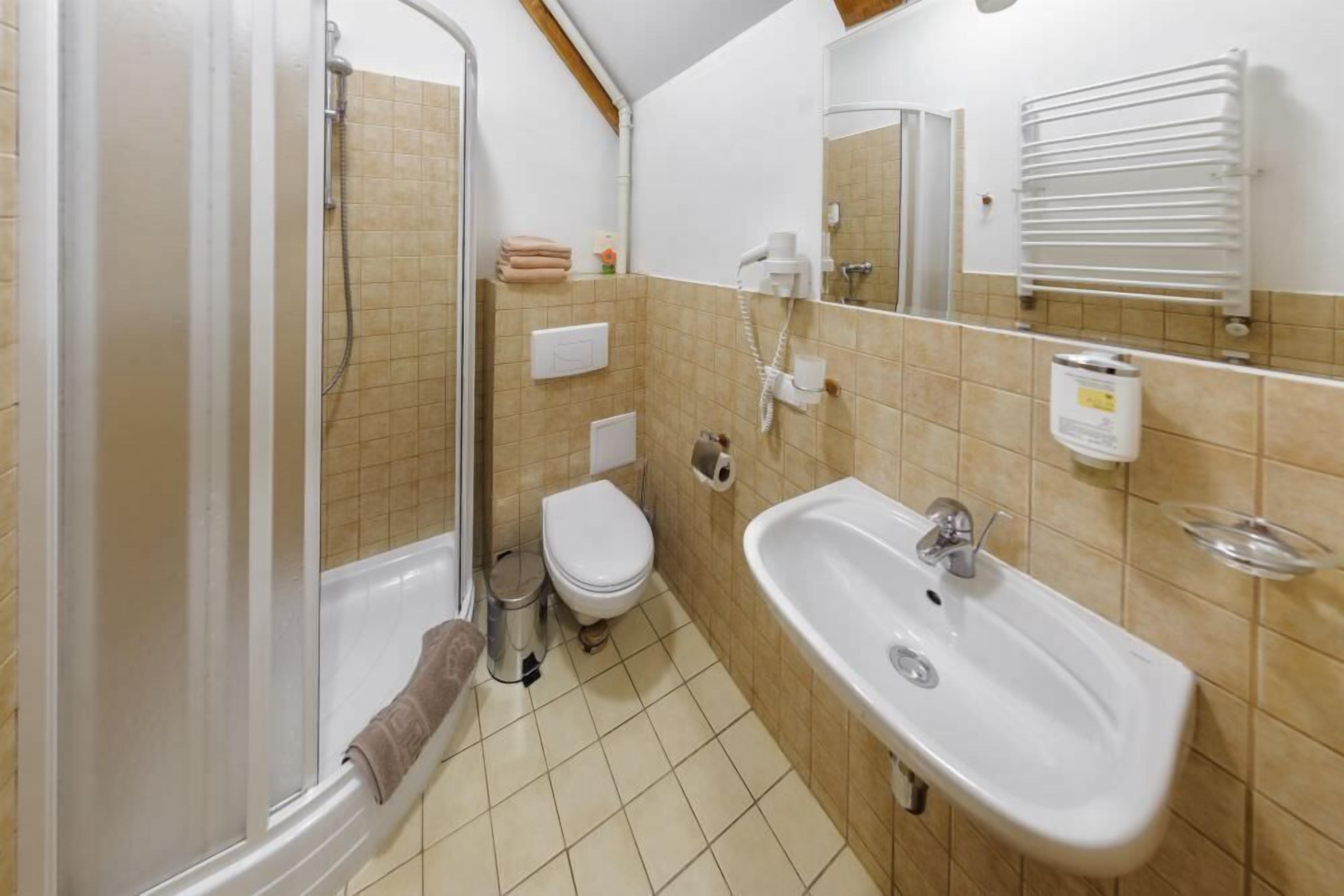 Une salle de bain équipée d’une douche, de toilettes, d’un lavabo et d’un porte-serviettes.