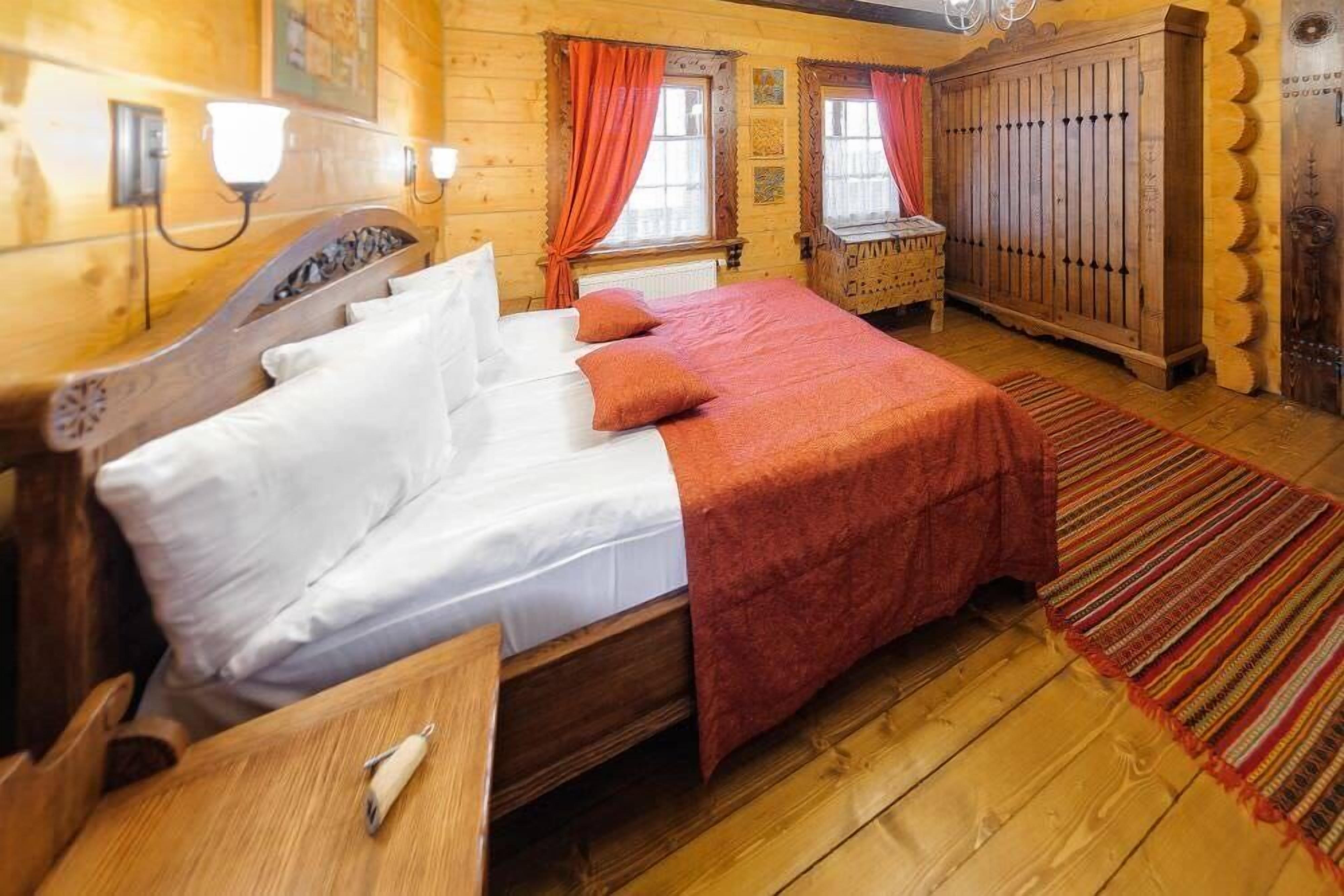 Una habitación de madera con una cama, un armario de madera y una ventana con cortinas.
