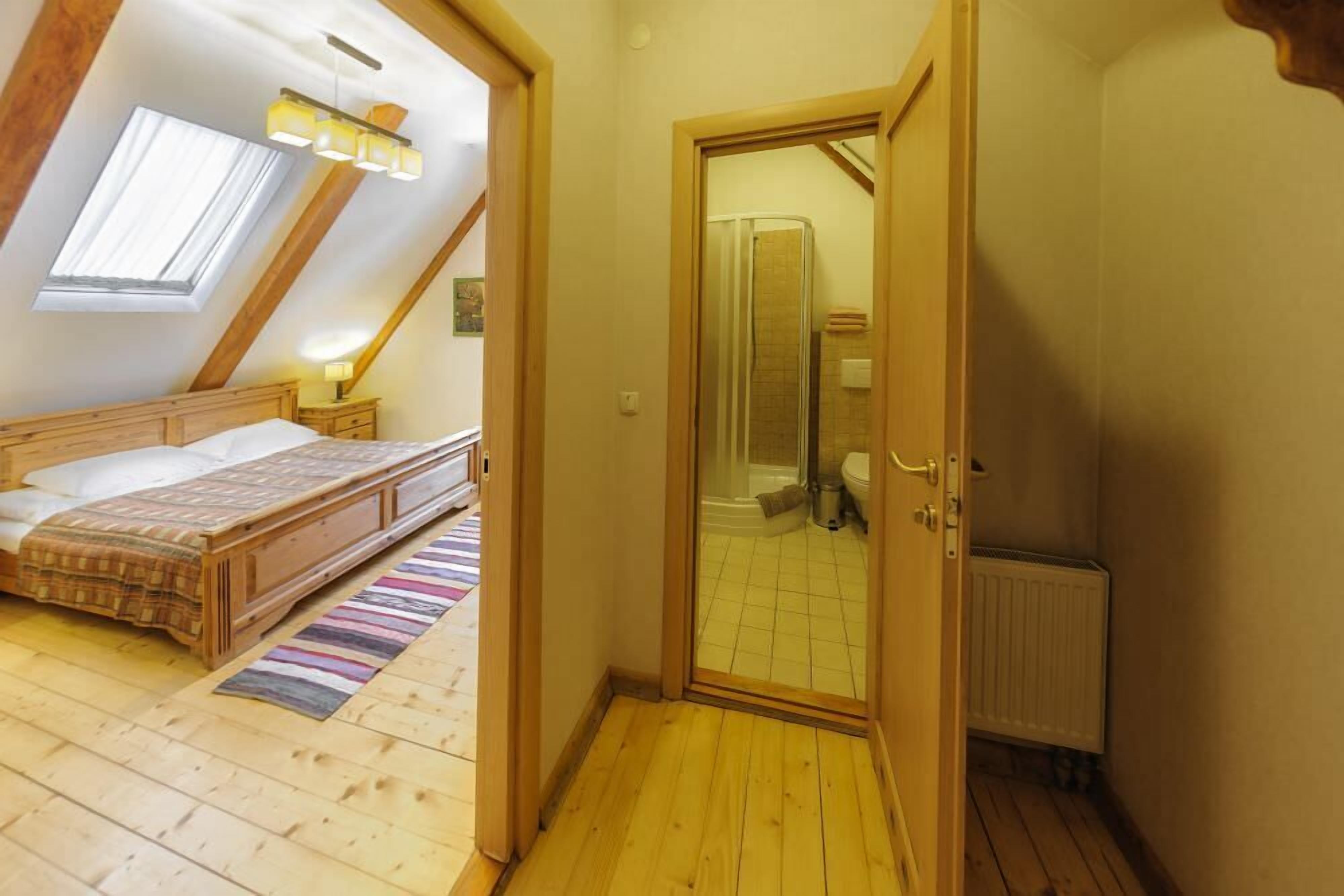 Une chambre à coucher avec un lit en bois, une table de chevet, une fenêtre avec des rideaux et un plafond en pente doté de lucarnes.