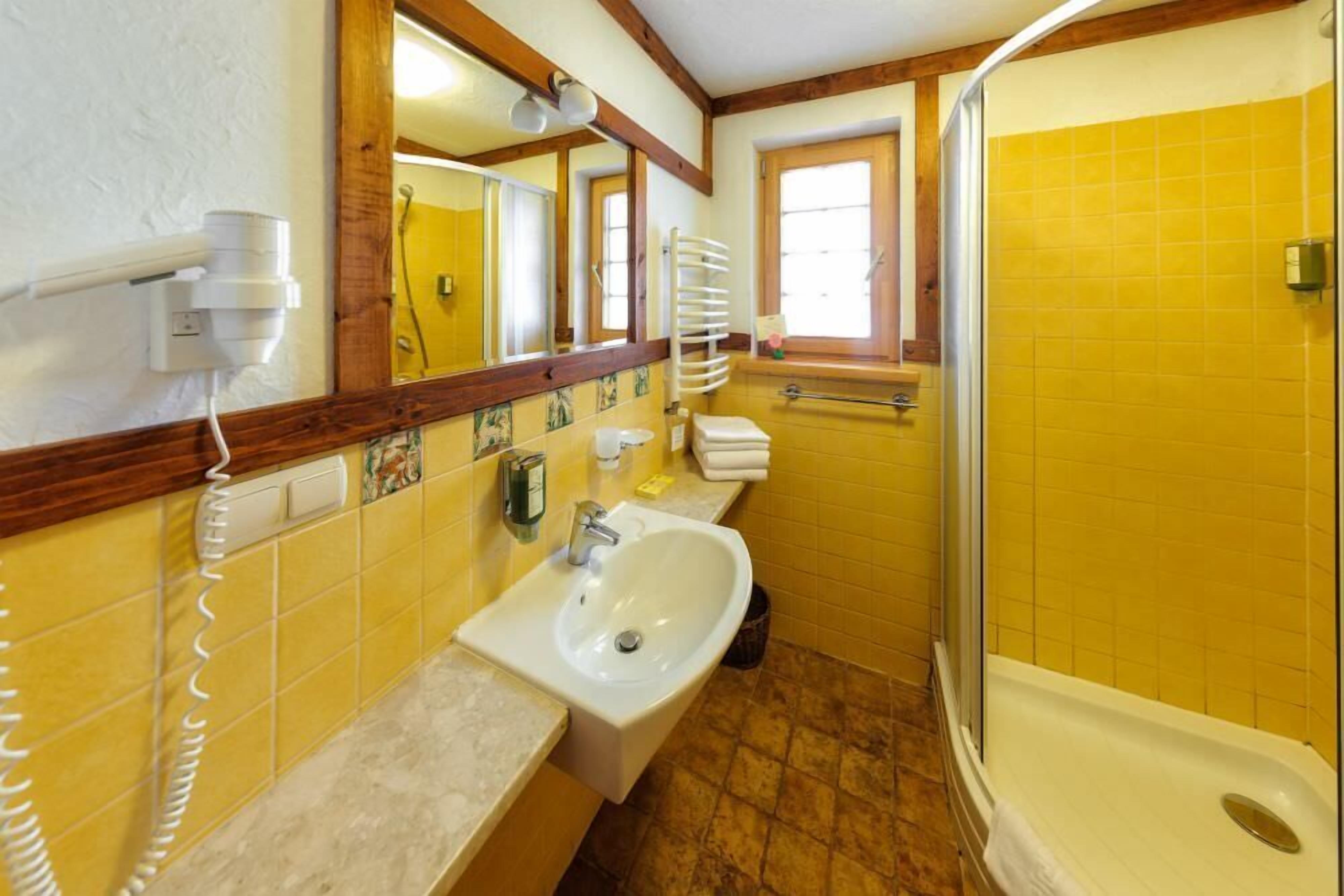 Casa de banho com lavatório, espelho e chuveiro.