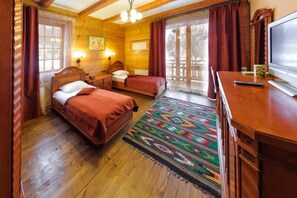 A wooden room with two beds, a TV, and a large window with curtains. - Koruna (Tatariv)