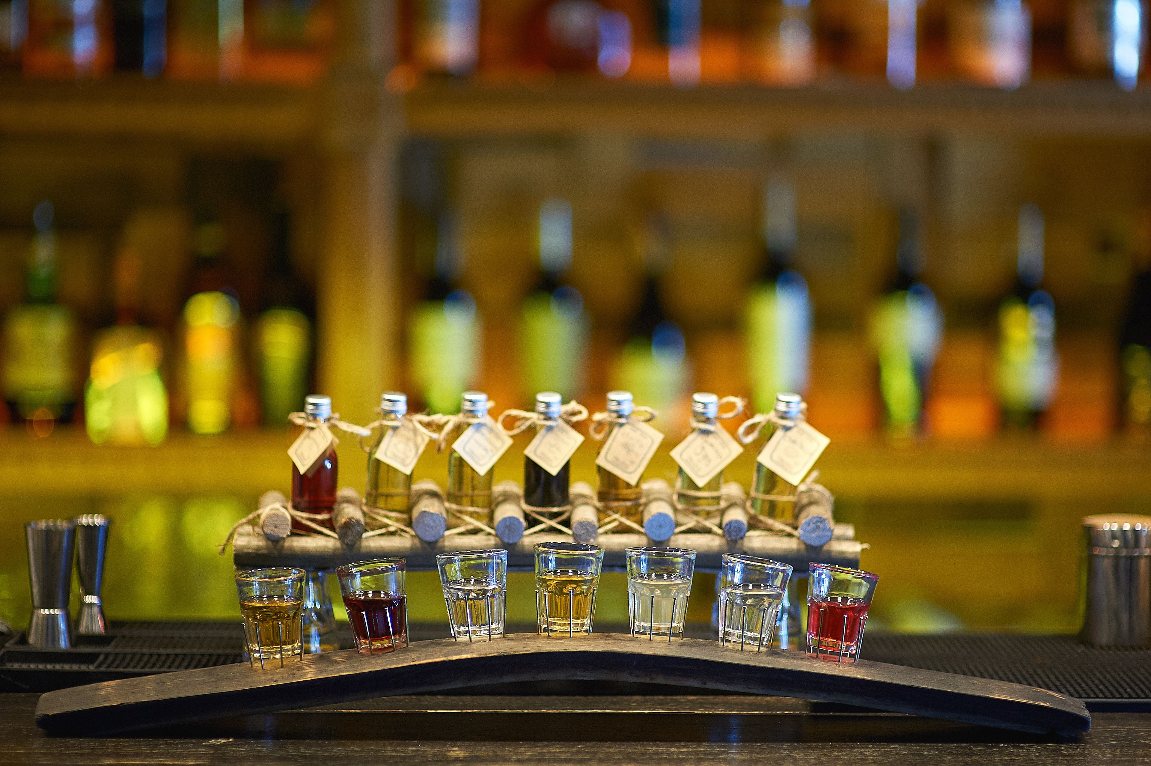 Una barra con una variedad de licores y vasos para chupitos dispuestos sobre el mostrador.