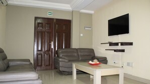 Una sala de estar moderna con un sofá, una mesa y un televisor montado.