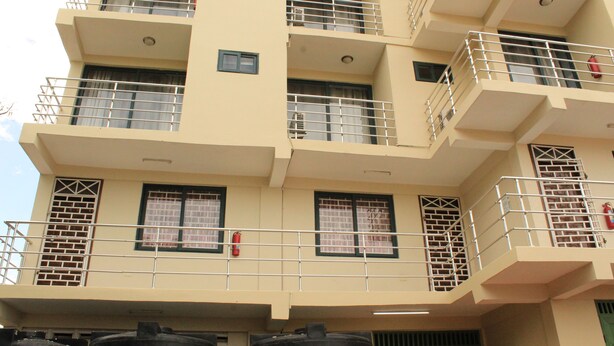 Un edificio de varios pisos con balcones, ventanas con contraventanas y un portón verde en la entrada.