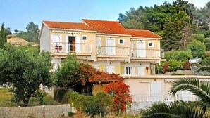A two-story building with balconies, surrounded by greenery and trees. - Kappatos Apartments (Kefalonia)