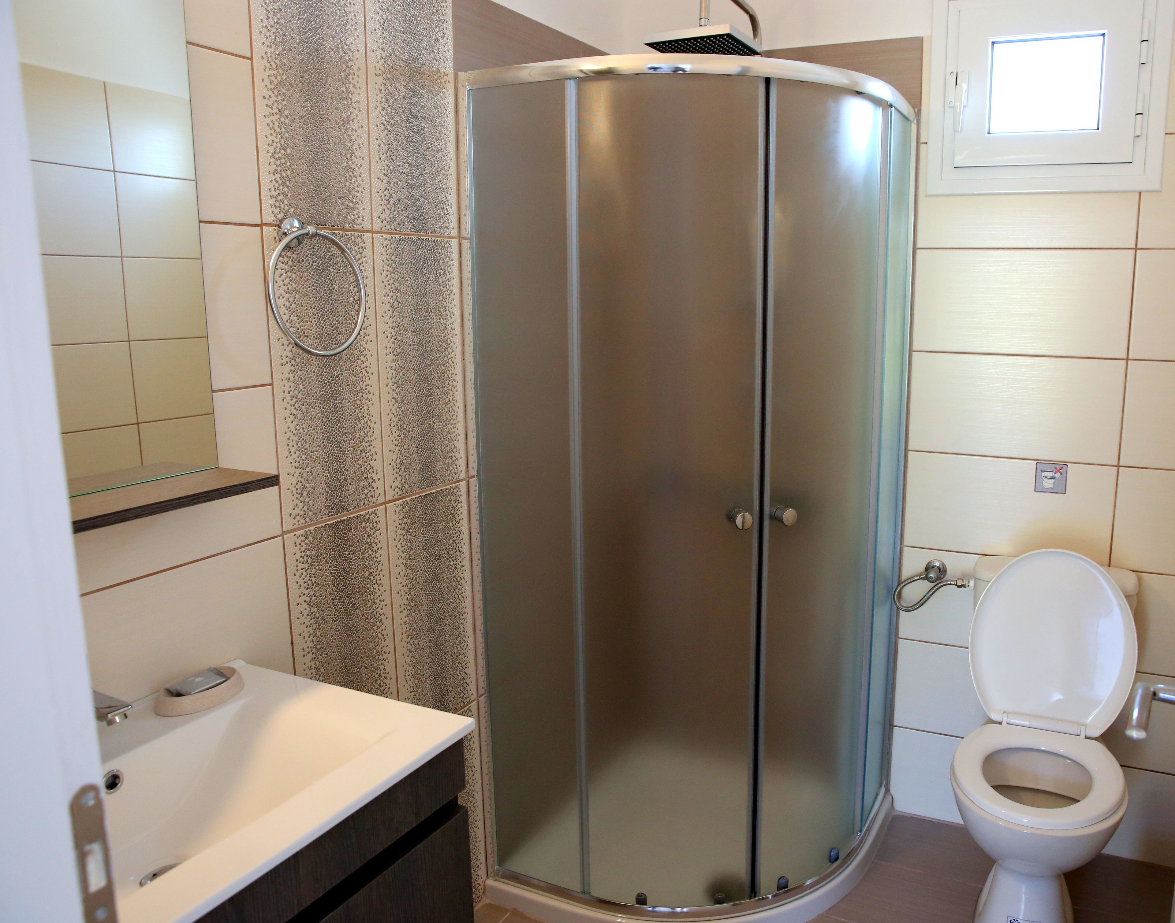 A bathroom with a glass-enclosed shower, a toilet, and a sink.