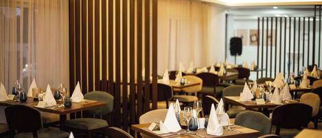 A restaurant with tables set for dining, featuring a modern interior design with wooden panels and a warm ambiance.