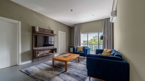 A modern living room with a flat-screen TV, a wooden coffee table, and a blue sofa with yellow cushions. - Central Hotel- Ridge (Accra)