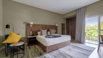 A modern bedroom with a large bed, a nightstand, a chair, and a view of the outdoors.