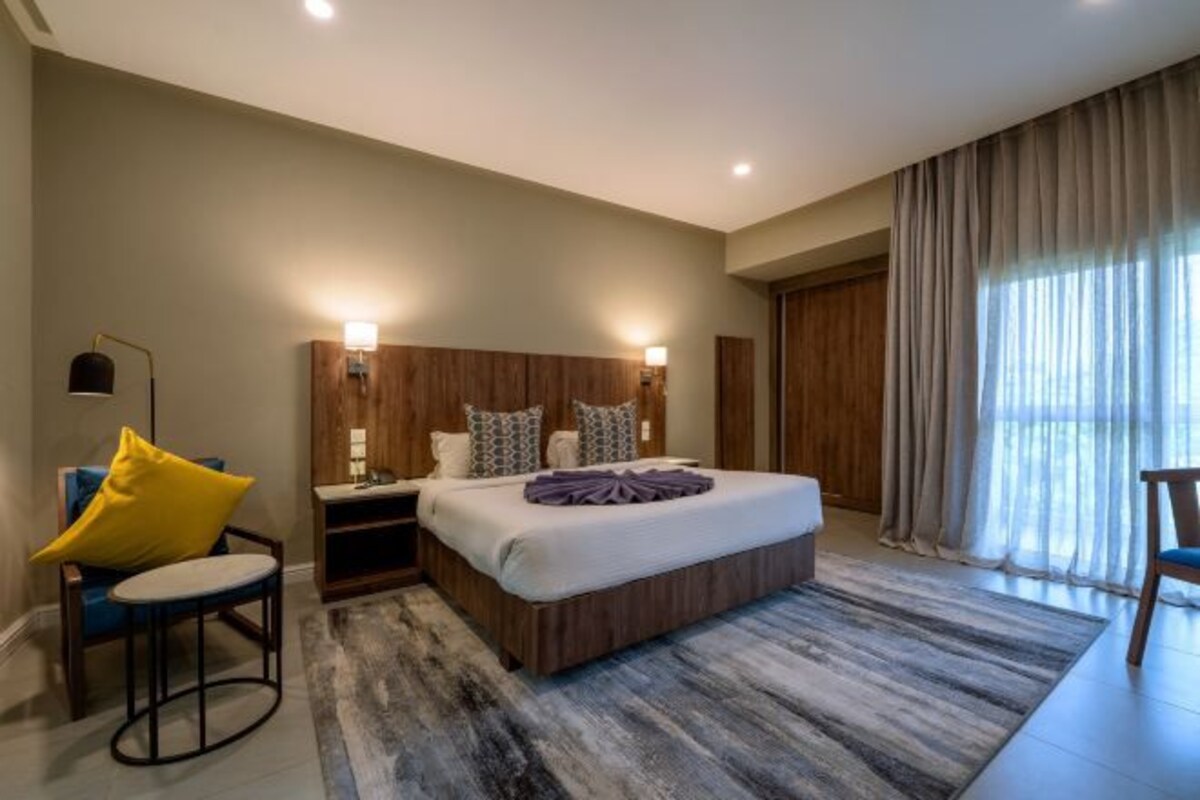Un dormitorio moderno con una cama grande, lámparas de noche, una silla y vistas al exterior.