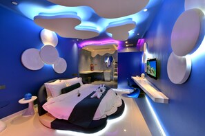 A modern bedroom with a curved bed, a vanity, and a TV on the wall. - Xiamen Aizhu Lover Hotel - Jimei Branch (Xiamen)