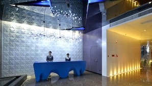 A reception area with a blue counter, a patterned wall, and a modern ceiling design. - Xiamen Aizhu Lover Hotel - Jimei Branch (Xiamen)