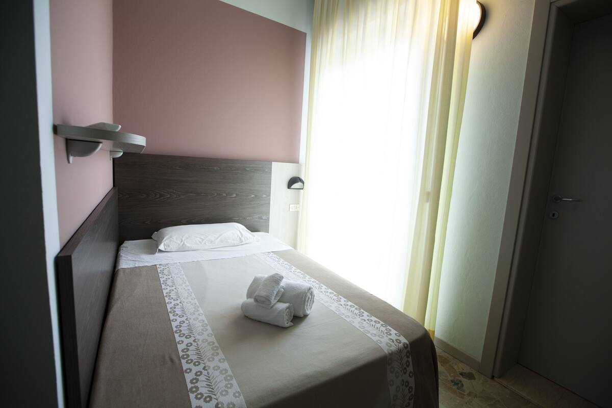 A neatly made bed with a headboard, a bedside table, and a wall-mounted light fixture.
