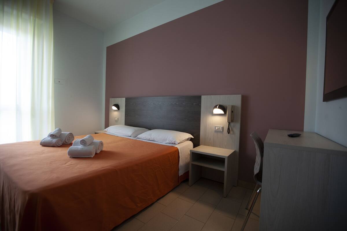 A hotel room with a bed, two bedside tables, a chair, and a desk.