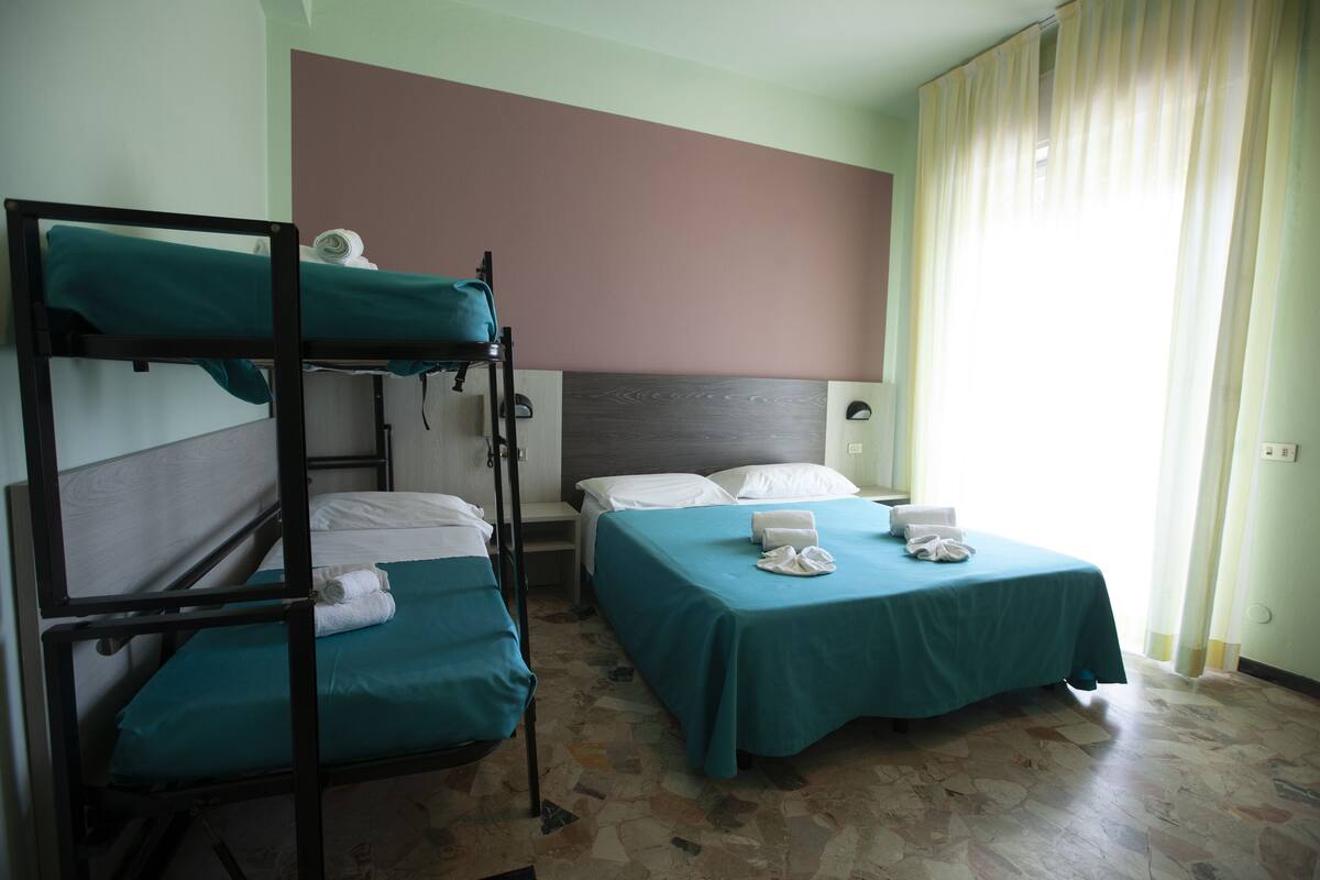 A room with bunk beds and a single bed, both with teal bedding.
