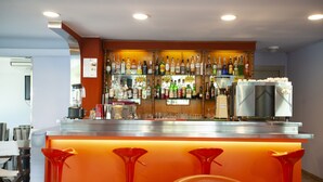 A bar area with a variety of liquor bottles, a refrigerator, and a coffee machine. There are four red bar stools in front of the bar. - Hotel Mirage Bellaria (Bellaria-Igea Marina)