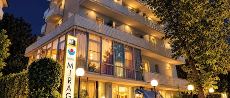 Um hotel com vários andares, varandas, amplas janelas e uma placa indicando ser o 'Mirage Hotel'.