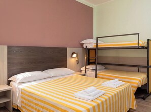 Ein Schlafzimmer mit Etagenbett, zwei Betten, jeweils mit gelbgestreifter Bettdecke und weißen Kissen. Ein Nachttisch mit Lampe und ein an der Wand befestigtes Telefon sind ebenfalls vorhanden.