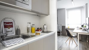Une cuisine moderne équipée d’un évier, d’un four à micro-ondes, d’une machine à café et d’un saladier rempli de fruits.