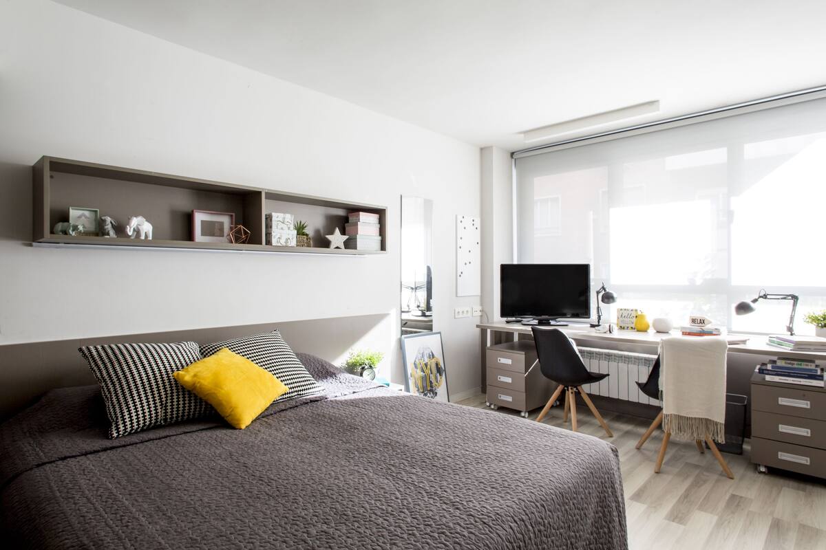 Une chambre moderne avec un lit, un bureau et une grande fenêtre.