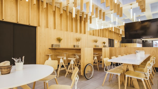Un restaurant moderne avec des murs en bois, des tables et des chaises blanches.