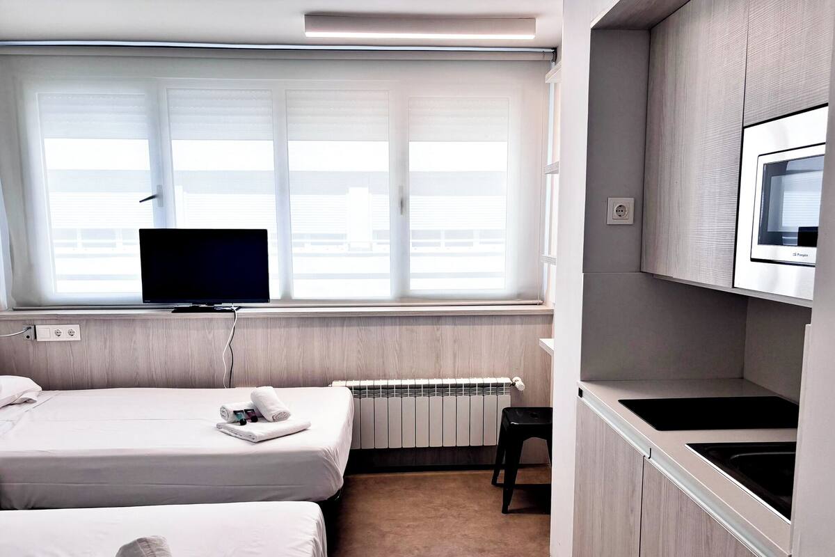 Une chambre d’hôtel avec deux lits, une télévision, un radiateur et une kitchenette.