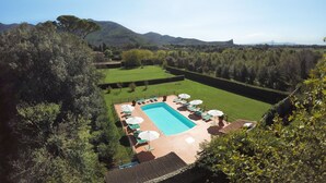 A pool area with lounge chairs and umbrellas, surrounded by well-manicured lawns and trees, with mountains in the background. - Agriturismo Villa Rosselmini (Calci)
