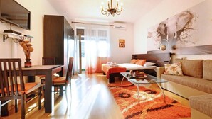 Ein modernes Wohnzimmer mit Essbereich, einer Couch, einem Bett und einer Chandelier.