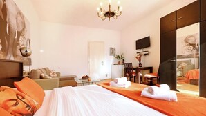 Ein Hotelzimmer mit einem großen Bett, einem Flachbildfernseher, einem Schreibtisch mit Stuhl, einem Spiegel und einem großen Fenster.