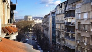 Ein mehrstöckiges Gebäude mit Balkonen, freier Sicht auf die Straße und ein entferntes Gebäude mit einer Kuppel.