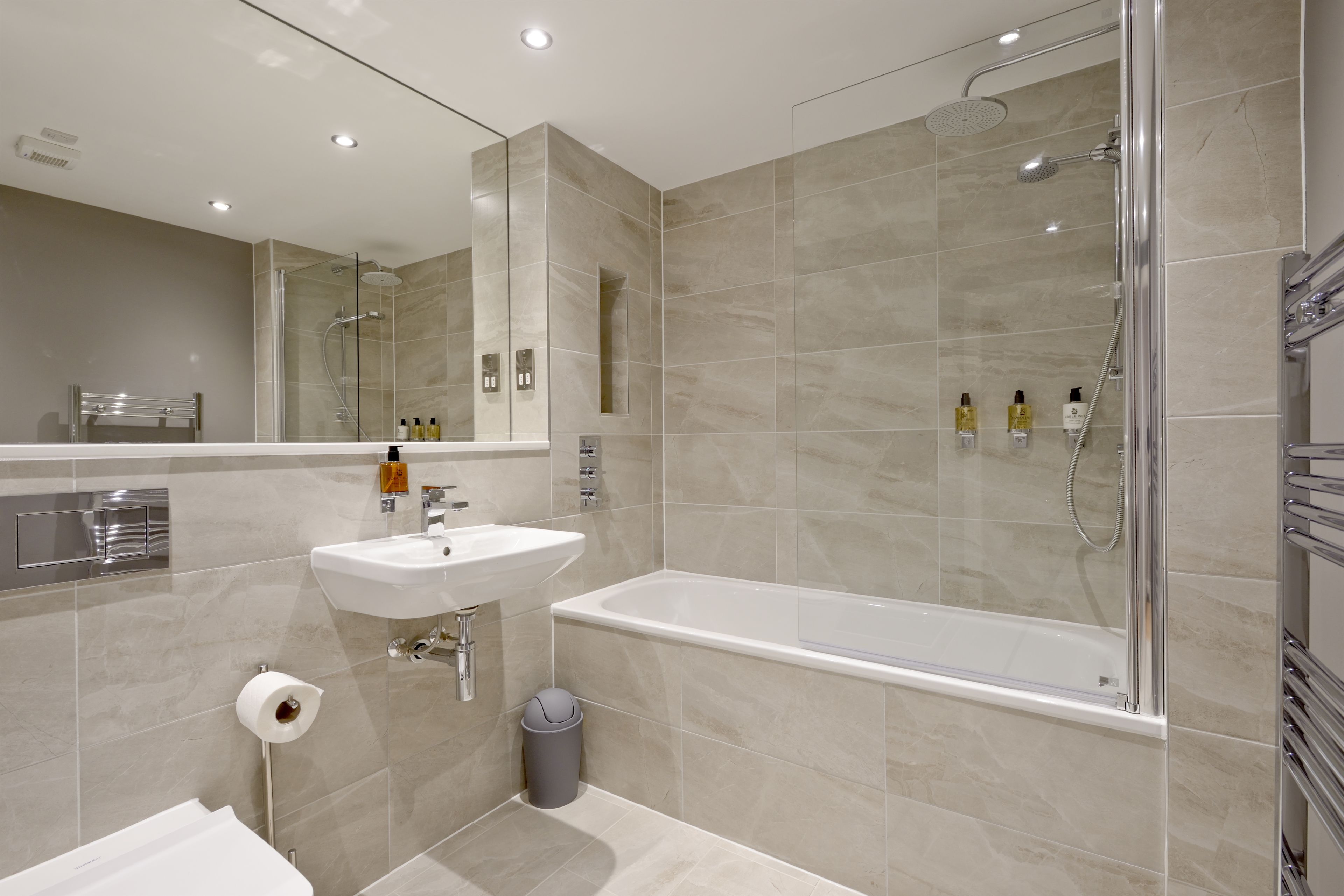 A modern bathroom with a glass-enclosed shower, a white sink, and a bathtub.