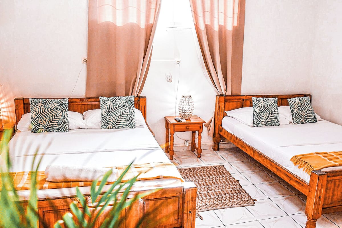 A double room with two beds, each with a wooden headboard, a bedside table, and a lamp.