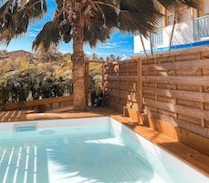 Una piscina con muelle de madera y palmeras al fondo.
