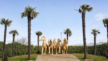 Een pad dat leidt naar een beeldhouwwerk van vier gouden paarden.